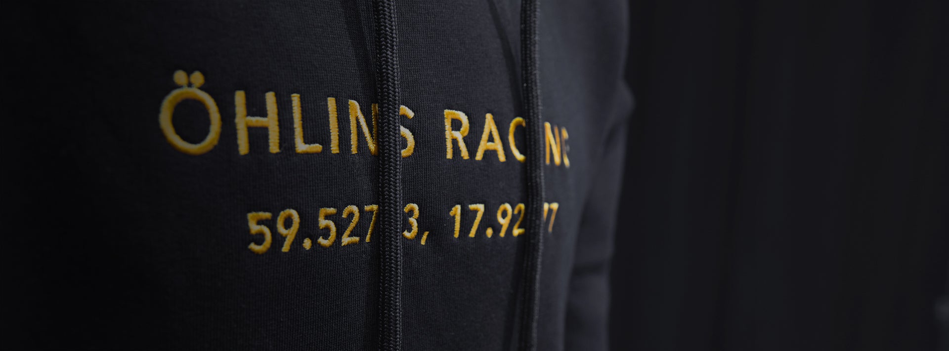 Öhlins merchandise: black hoodie with yellow embroidered 'Öhlins Racing' text.